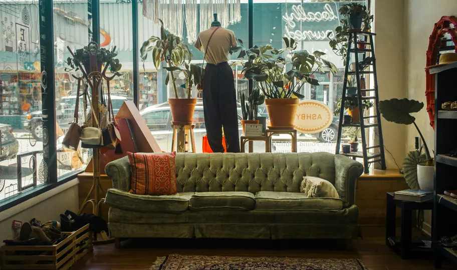 A thrift shop floor with a green tufted sofa by a sunny window (stock photo for illustration)