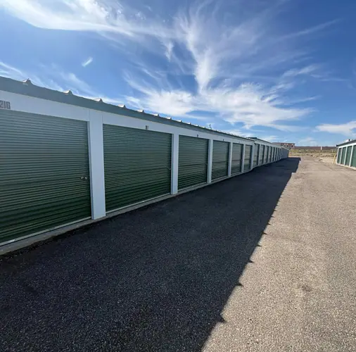 A row of self-storage units with green roll-up doors