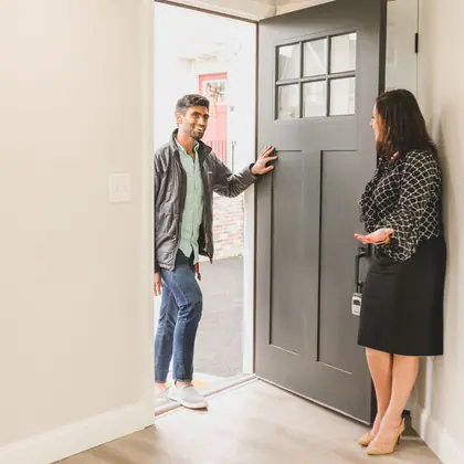 A realtor greeting someone at a front door