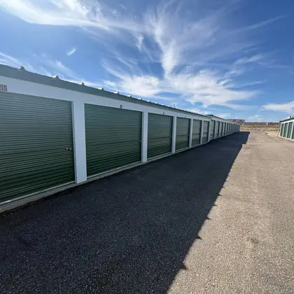 A row of storage units with green roll-up doors